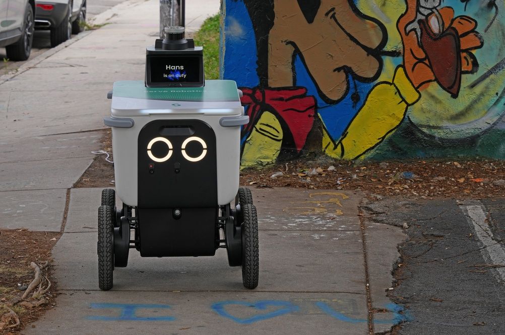 Autonomous sidewalk delivery robot next to a street mural